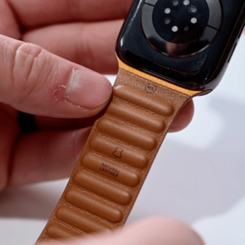 Correa Leather Link de Apple Watch sostenida en la mano, con el reverso de piel natural a la vista